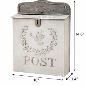 May include: A rectangular, off-white metal mailbox with a decorative top and a keyhole. The front features a dove and wreath design, with the word "POST" below. It measures 10 inches wide, 3.4 inches deep, and 14.6 inches tall.