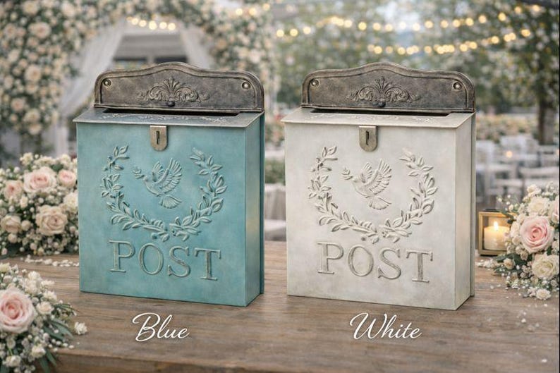 May include: Two decorative metal mailboxes, one blue and one white, with a vintage design. Each mailbox features a dove and laurel wreath motif, the word "POST", and a decorative lid. The blue mailbox is labeled "Blue", and the white mailbox is labeled "White".