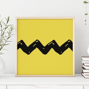 May include: A framed print with a yellow background and a black zig-zag pattern, reminiscent of the character Charlie Brown's shirt.