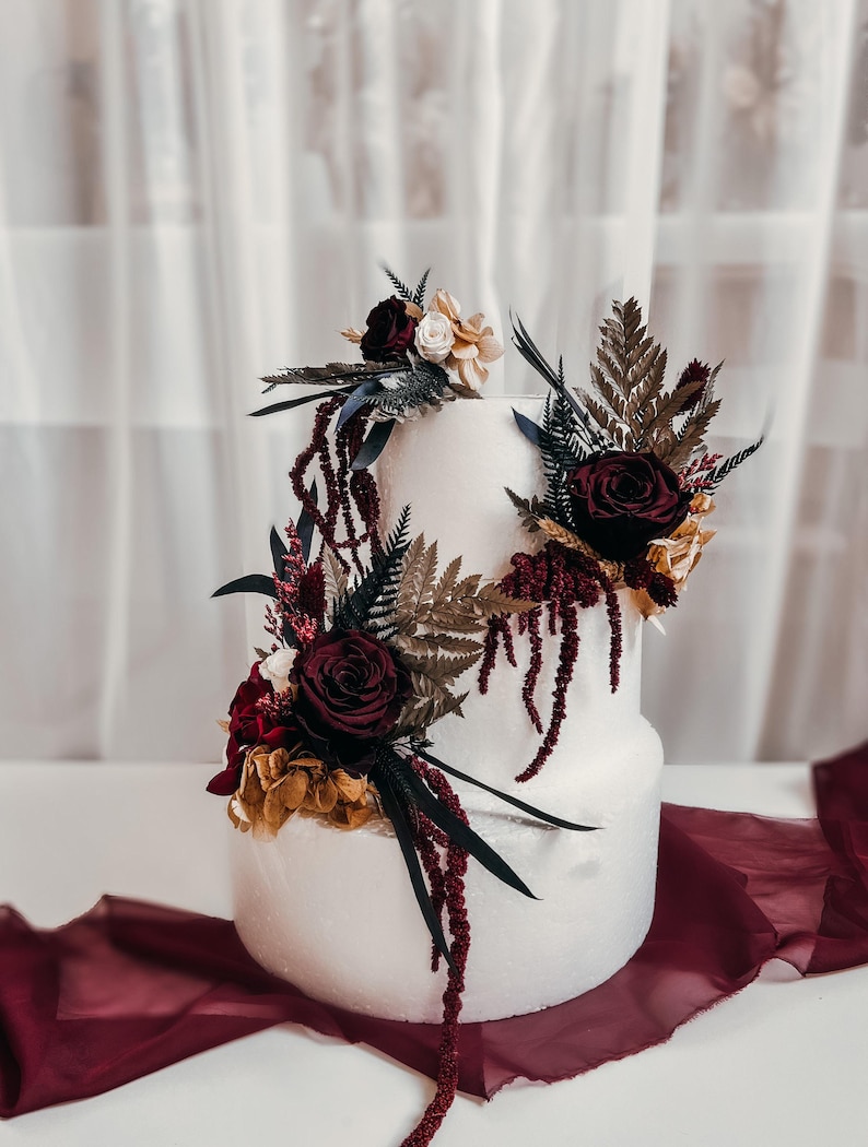 Burgundy wedding cake flowers with preserved roses, amaranthus, eucalyptus and dried florals in moody wine red tones. Gothic boho cake topper set for romantic fall wedding cake decor. Dramatic preserved flower cake decorations for elegant burgundy wedding themes and modern moody weddings.