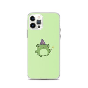 Pode incluir: Uma capa de telefone transparente com fundo verde e um sapo de desenho animado usando um chapéu de mago roxo e segurando uma varinha mágica. A capa do telefone é compatível com um iPhone 13 Pro.