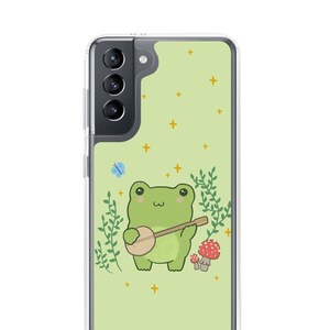 May include: A green frog playing a banjo in a green forest with a blue butterfly and red mushrooms. The frog is wearing a banjo strap and has a happy expression. The background is a light green with yellow stars.