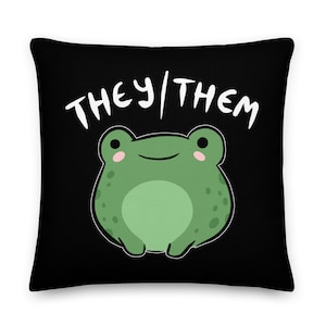 Puede incluir: Almohada negra con una rana blanca y el texto "THEY/THEM" en blanco.