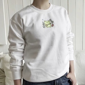 May include: White sweatshirt with a green frog playing a guitar embroidered on the front.