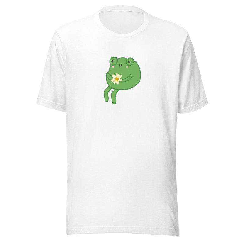 May include: White t-shirt with a green frog holding a white flower.