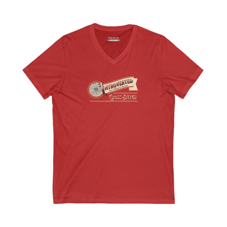 Op de afbeelding: Rood V-hals T-shirt met de tekst "Introvert maar bereid om kruissteek te bespreken" in een bannerontwerp. Het shirt heeft een cirkelvormige afbeelding met kruissteekelementen.