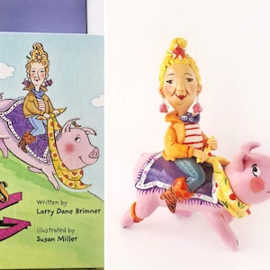 May include: A pink pig with a yellow and white scarf is being ridden by a woman with blonde hair and a yellow jacket. The woman is wearing a blue and white striped shirt and blue jeans. The pig is wearing a purple and blue saddle. The book cover reads "Grandma's Pig" with the author and illustrator's names listed below.