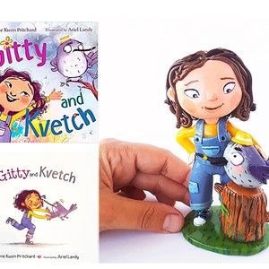 May include: A handmade figurine of a girl with brown hair wearing a yellow shirt and blue overalls. She is standing next to a small bird with a yellow hat on a tree stump. The figurine is based on the children's book "Gitty and Kvetch" by Caroline Kusin Pritchard, illustrated by Ariel Landy.