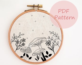 May include: A black and white embroidery pattern of mushrooms and flowers on a beige fabric in a round embroidery hoop. The hoop is labelled "PDF Pattern".