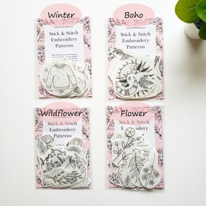 May include: Four packs of stick and stitch embroidery patterns are displayed. Each pack has a different theme: Winter, Boho, Wildflower, and Flower. The patterns are black line drawings on white fabric, packaged in clear plastic with pink backing.