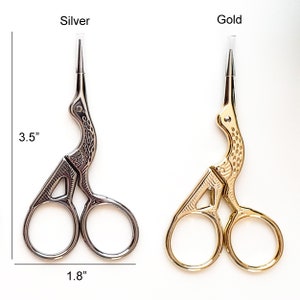 May include: Silver and gold-colored embroidery scissors. The silver scissors are 3.5 inches long and 1.8 inches wide. The gold scissors are the same size. Both scissors have a bird-like design and are on a white background.