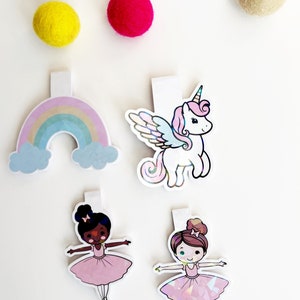 May include: Four colorful bookmarks with a rainbow, a unicorn, and two ballerinas. The bookmarks are made of iridescent paper and have a white backing.