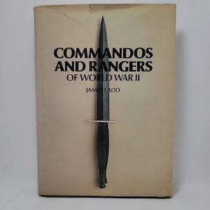 May include: A book cover with the title "Commandos and Rangers of World War II" by James Ladd. A black knife is centered on the cover.