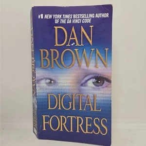 May include: A blue paperback book with a gold title, "Digital Fortress", by Dan Brown, the #1 New York Times bestselling author of "The Da Vinci Code".