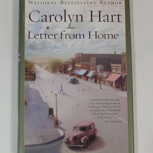 May include: A book cover with a green border and a vintage illustration of a small town street scene. The title of the book is "Letter from Home" by Carolyn Hart. The book cover also includes a quote from Tony Hillerman.