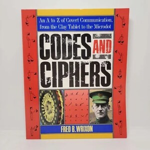 May include: A book titled "Codes and Ciphers" with a red, yellow, and blue cover. The cover features the title in large, bold letters, along with images and text. The author's name, Fred B. Wrixon, is also visible.