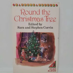 May include: A Young Puffin book titled "Round the Christmas Tree" edited by Sara and Stephen Corrin. The cover illustration depicts a decorated Christmas tree with children gathered around it. The book has a red and white title.