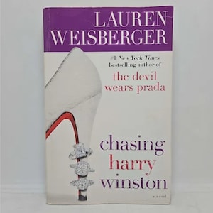 May include: A paperback book titled "Chasing Harry Winston" by Lauren Weisberger. The cover features a white high-heeled shoe with a red sole and three diamond rings. The author is also the author of "The Devil Wears Prada".
