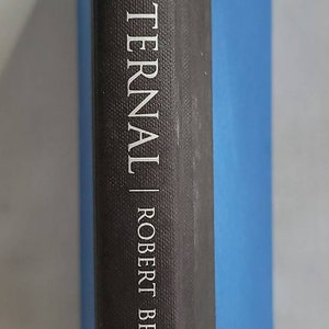 May include: A black hardcover book with a blue spine. The title "WE ARE ETERNAL" by Robert Brown is printed in silver on the front cover. The Warner Books logo is printed in silver on the bottom of the front cover.