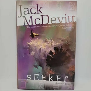 May include: A paperback book titled "Seeker" by Jack McDevitt. The cover features a space scene with a dark spaceship and a purple and white background. The book has a quote from Stephen King.