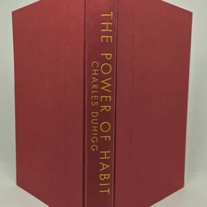 May include: A red hardcover book with the title "The Power of Habit" by Charles Duhigg in gold lettering on the spine.