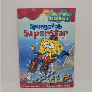 May include: A book cover featuring Spongebob Squarepants as a superhero riding a bike with a star on his helmet. The title of the book is "Spongebob Superstar" and the book is written by Annie Auerbach and illustrated by Mark O'Hare.