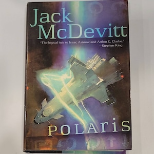 May include: A book cover with a dark blue background and a spaceship flying through a bright blue and yellow nebula. The title "POLARIS" is written in white letters on the bottom of the cover. The author's name "Jack McDevitt" is written in white letters at the top of the cover. A quote from Stephen King is written in white letters below the author's name: "The logical heir to Isaac Asimov and Arthur C. Clarke."