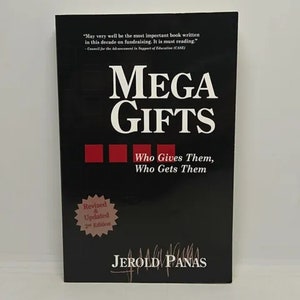 May include: A black book cover with the title "MEGA GIFTS" in white text. The subtitle is "Who Gives Them, Who Gets Them" in smaller white text. The book cover also features a red star with the text "Revised & Updated 2nd Edition".