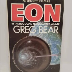 May include: A book cover with a black background and the title "EON" in large red letters. The subtitle is "An Epic of the Future" and the author is "Greg Bear". The cover features a black and white image of a planet with a galaxy in the background.