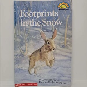 May include: A children's book cover featuring a brown rabbit hopping through a snowy forest. The title is "Footprints in the Snow" and the book is part of the "Hello Reader" series, level 1. The book is published by Scholastic.