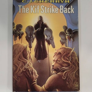 May include: A paperback book titled "The Kif Strike Back" by C.J. Cherryh. The cover art features a hooded figure, several skull-like faces, and two humanoid figures with animalistic features, set against a yellow and blue background.