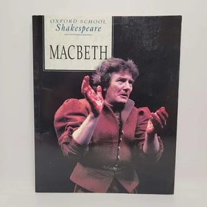 May include: A book cover featuring a man in a red costume with blood on his hands. The title of the book is "Macbeth" and the series is "Oxford School Shakespeare".
