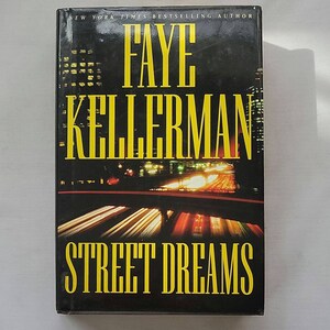 May include: A black paperback book with a yellow title, "Street Dreams", by author Faye Kellerman. The cover features a blurred image of a highway at night with bright lights.