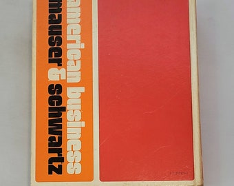 May include: A white book with an orange spine. The spine has the text "american business mauser & schwartz" in black.