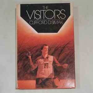 May include: The Visitors, a novel by Clifford D. Simak, is featured on the cover of this paperback book. The cover art depicts a man in a field of tall grass, holding a device in his hand. The background is a vibrant orange and red sunset.