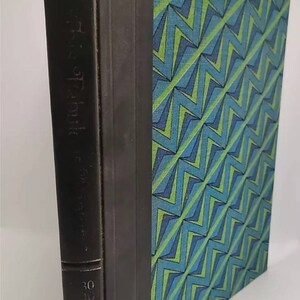 May include: A black hardcover book with a green and blue geometric pattern on the cover. The spine of the book has the text "The Complete Works of Edgar Allan Poe" and the number "30" printed on it.