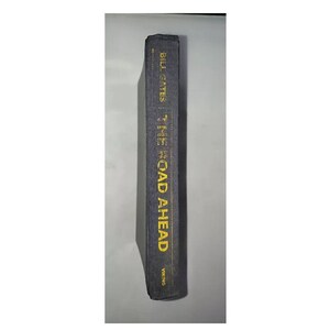 May include: A black hardcover book with the title "The Road Ahead" by Bill Gates in yellow text on the spine.