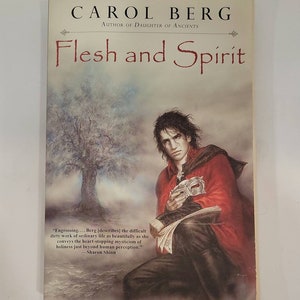 May include: A book cover with a red, white, and black color scheme. The title "Flesh and Spirit" is written in a large, bold font. The author's name, "Carol Berg", is written in a smaller font below the title. The cover features a painting of a man with long black hair wearing a red cloak and holding a mask. The quote "Engrossing... Berg [describes] the difficult dirty work of ordinary life as beautifully as she conveys the heart-stopping mysticism of holiness just beyond human perception." -Sharon Shinn is printed at the bottom of the cover.