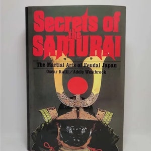 May include: Book cover with the title "Secrets of the Samurai: The Martial Arts of Feudal Japan" by Oscar Ratti and Adele Westbrook. The cover features a samurai warrior in full armor with a red circle in the background.