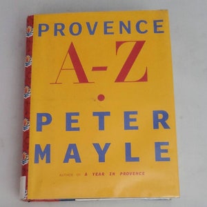 May include: A yellow book cover with the title "Provence A-Z" by Peter Mayle, author of "A Year in Provence".