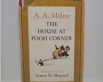 May include: A yellow book cover with the title "The House at Pooh Corner" by A.A. Milne. The cover features illustrations of Winnie the Pooh and Piglet in the snow.