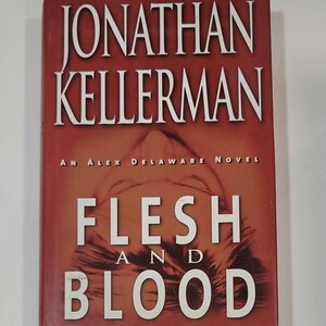 May include: A red hardcover book with the title "Flesh and Blood" by Jonathan Kellerman. The book is an Alex Delaware novel.