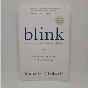 May include: A white book cover with the title "blink" in blue text. The book is by Malcolm Gladwell and is described as "The Power of Thinking Without Thinking".