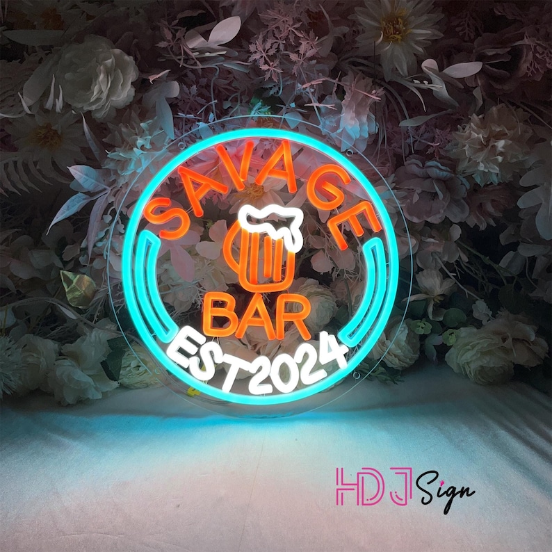 May include: Neon sign with a blue and orange circle. The circle says "Savage Bar Est 2024" with a beer mug icon in the centre.