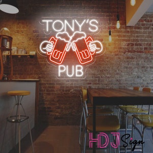 Op de afbeelding: Een wit neonbord met de tekst "TONY'S PUB" en een rood neonbeeld van twee bierglazen die klinken.