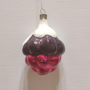 May include: A hanging glass ornament shaped like a cluster of berries. The top section is white, transitioning into a dark purple middle layer, and finishing with a bright, reflective pink bottom section. It features a metallic cap and a thin wire loop.