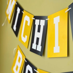 May include: A black and yellow banner with the word "MICHIGAN" in white letters.