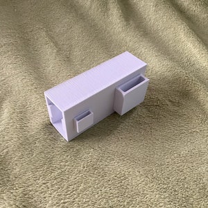 Puede incluir: Un organizador de escritorio de plástico blanco con tres compartimentos. El organizador tiene una forma rectangular y está diseñado para guardar bolígrafos, lápices y otros artículos de oficina.