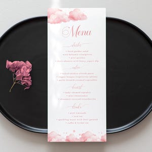 May include: A black round plate with a menu card and a pink flower. The menu card has a pink cloud design and the word "Menu" in pink script. The menu lists dishes, main courses, desserts, and drinks.