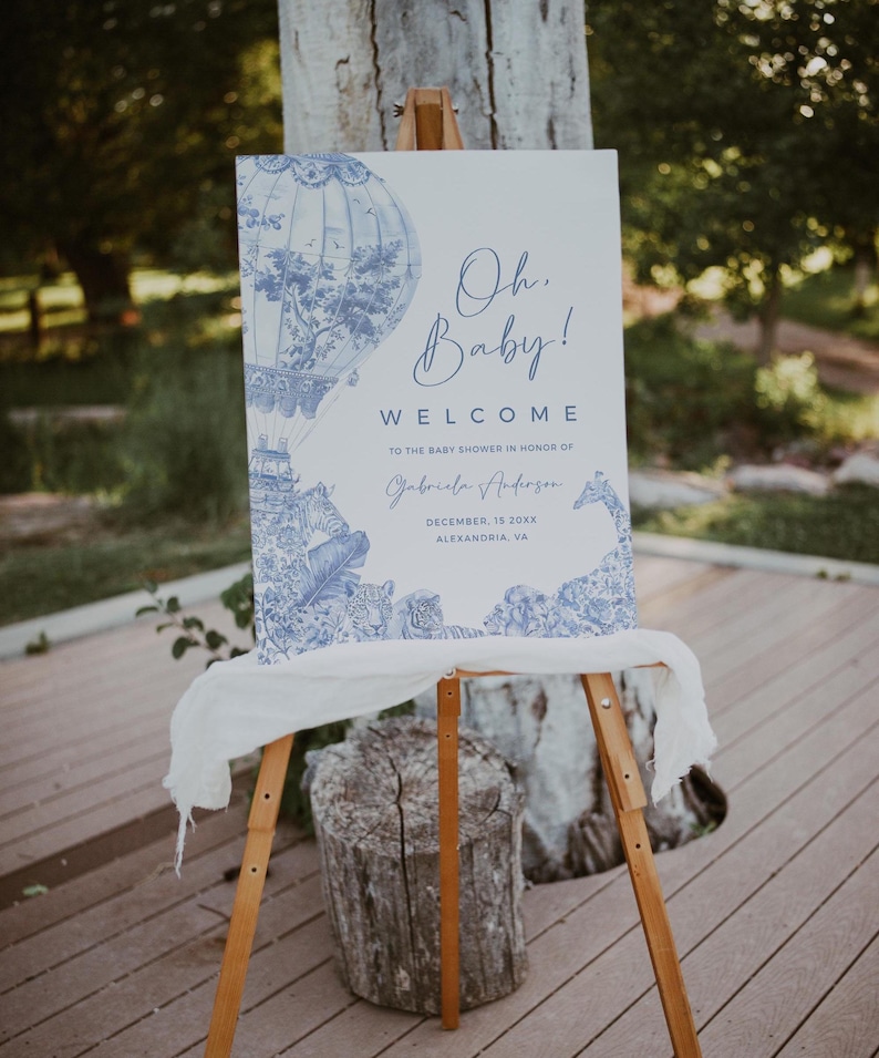 May include: A blue and white welcome sign for a baby shower with a hot air balloon and animal illustrations. The sign reads "Oh Baby! Welcome to the baby shower in honor of Gabriela Anderson, December 15, 20XX, Alexandria, VA."
